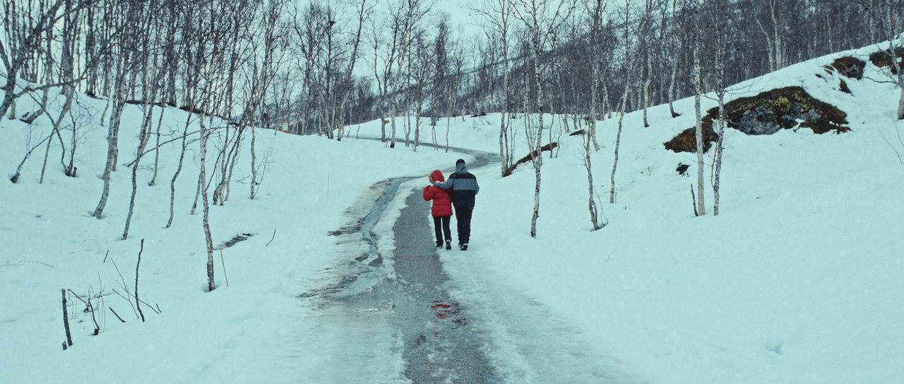 Two people walking together on a snowy road